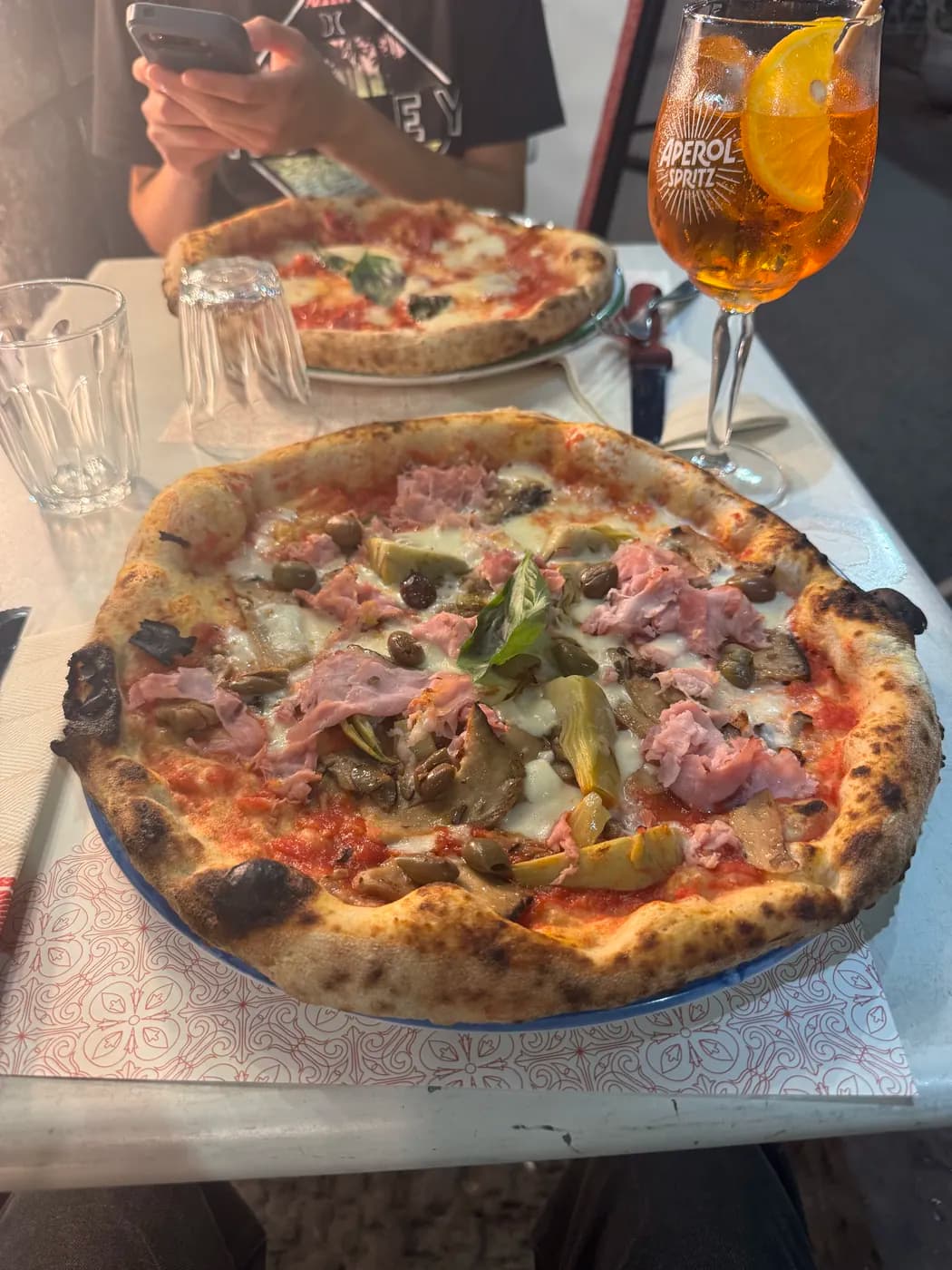 A pizza and an Aperol spritz on a restaurant table