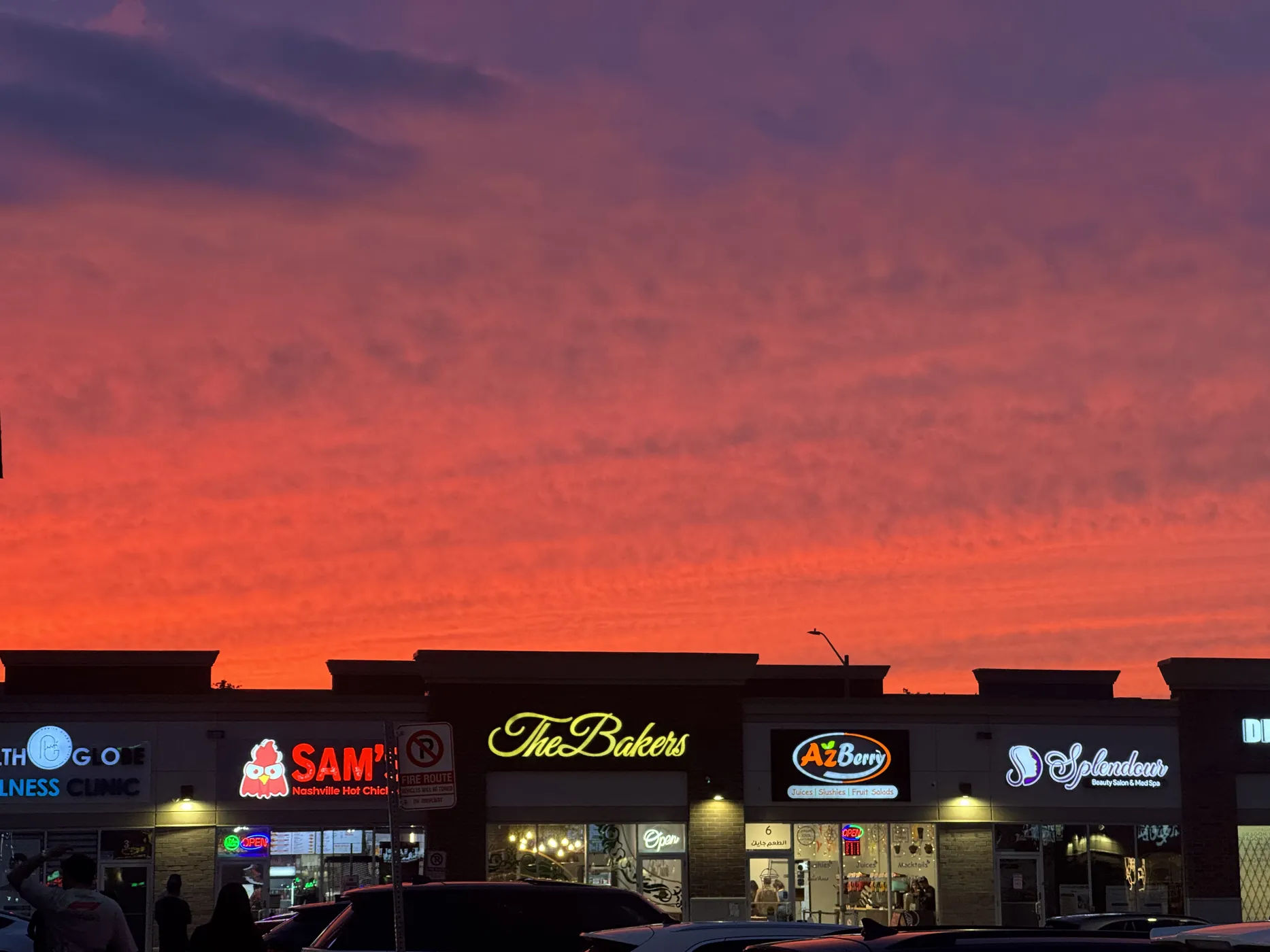 A suburban plaza under an orange and pink sunset